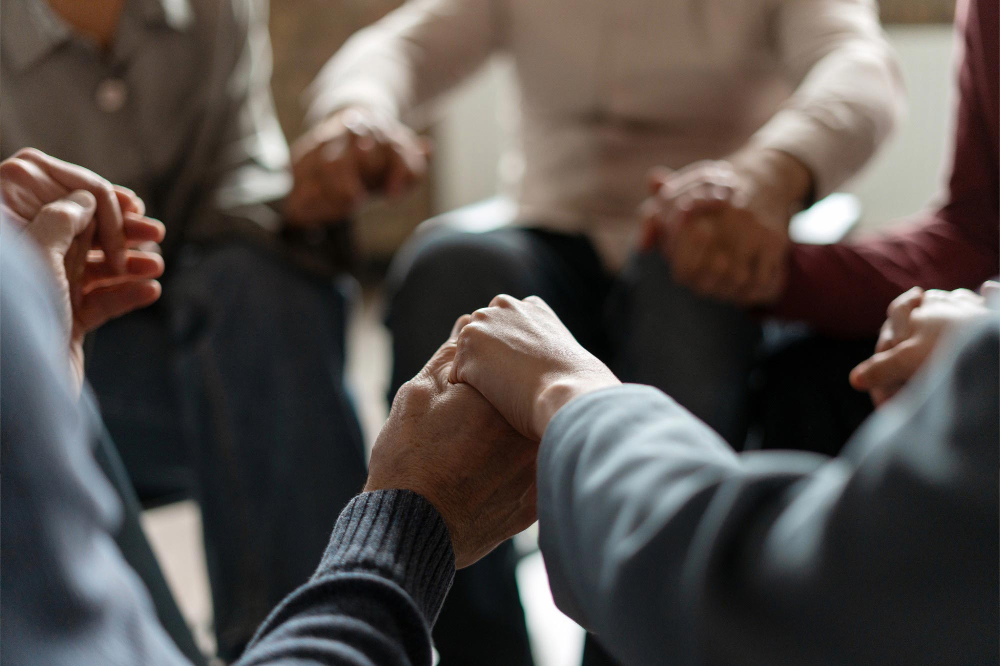 Group members holding hands in a supportive circle.